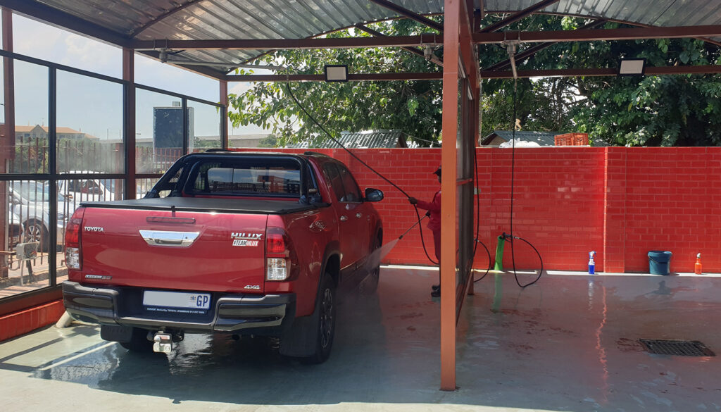 A person washing a car at a South African carwash business.